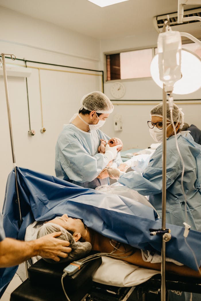 services-02 Medical professionals delivering a newborn in an operating room, showcasing teamwork and care.