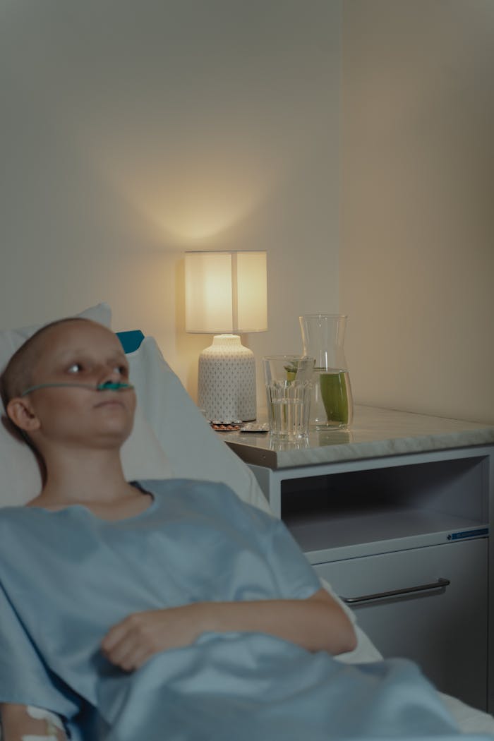 services-03 A woman patient with a nasal cannula lying in a hospital bed, appearing contemplative and calm.